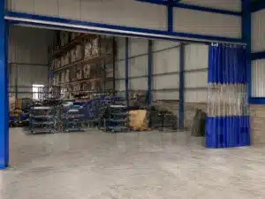 Cortina industrial corrediza divisoria abierta para el paso en un galpon separando ambientes